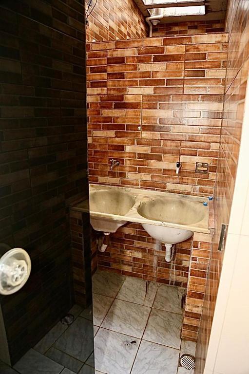 a bathroom with a sink and a brick wall at Studio 01 térreo in Goiânia