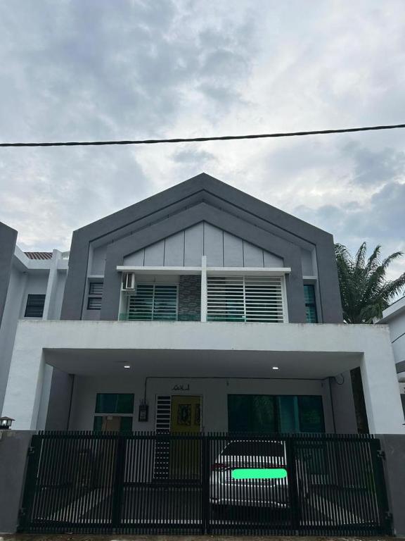 a white house with a black fence in front of it at Singgah homestay 2 in Sitiawan