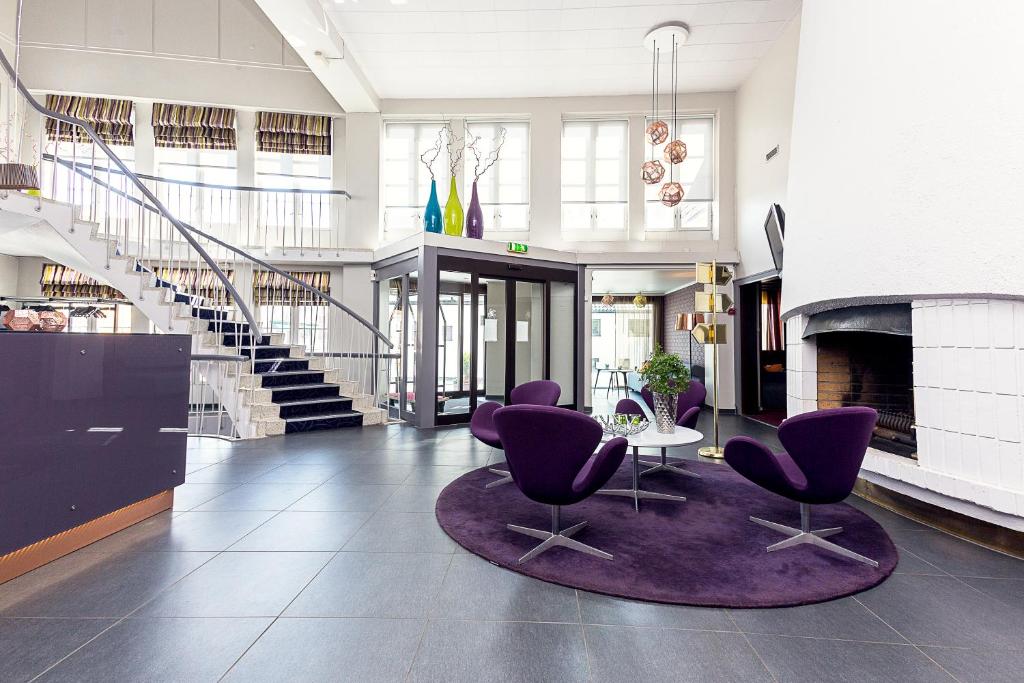 - un hall avec des chaises violettes, une table et des escaliers dans l'établissement Hotell Vic Porsgrunn, à Porsgrunn