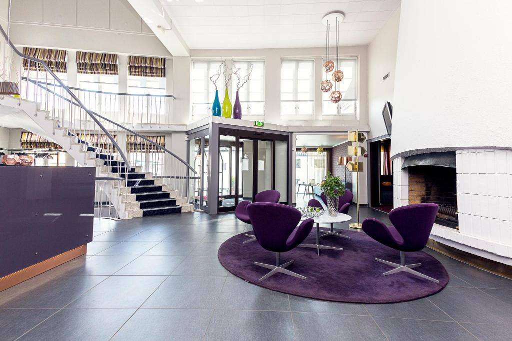 a lobby with purple chairs and a table and stairs at Hotell Vic Porsgrunn in Porsgrunn