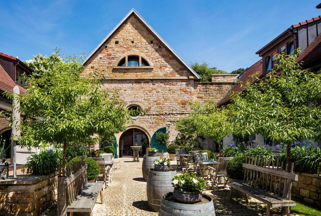 ein Gebäude mit einem Innenhof mit Bäumen und Bänken in der Unterkunft Loblocher Hof in Neustadt an der Weinstraße