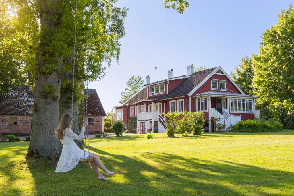 Una mujer con un vestido blanco sentada en un árbol en Åkagårdens Lodge, en Båstad