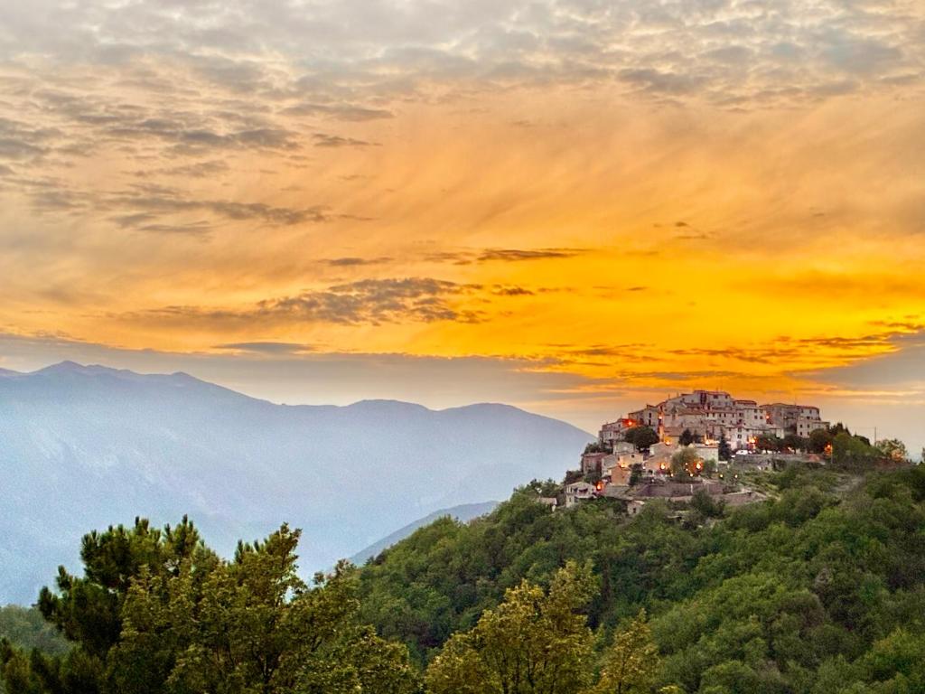 a village on a hill in the mountains at sunset at Chambres d'hôtes Les Nymphéas in Revest-les-Roches