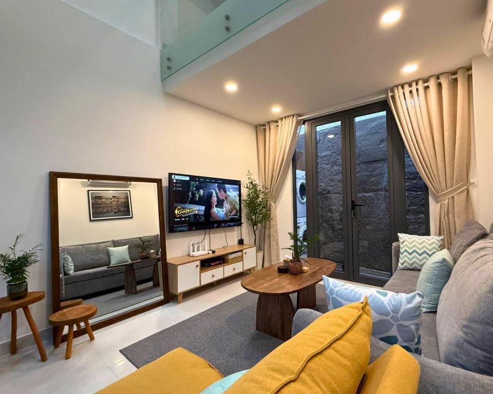 a living room with a couch and a tv at LYLAC Home Saigon NTMK - City Center Spacious Modern Townhouse Roof Terrace in Ho Chi Minh City