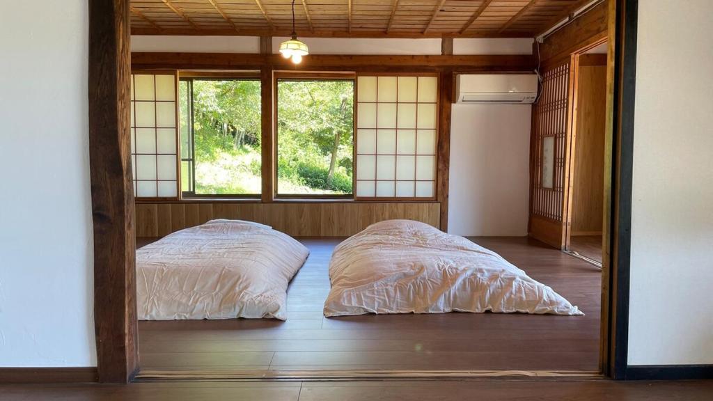two beds in a room with a window at 古民家かぐら in Tōno