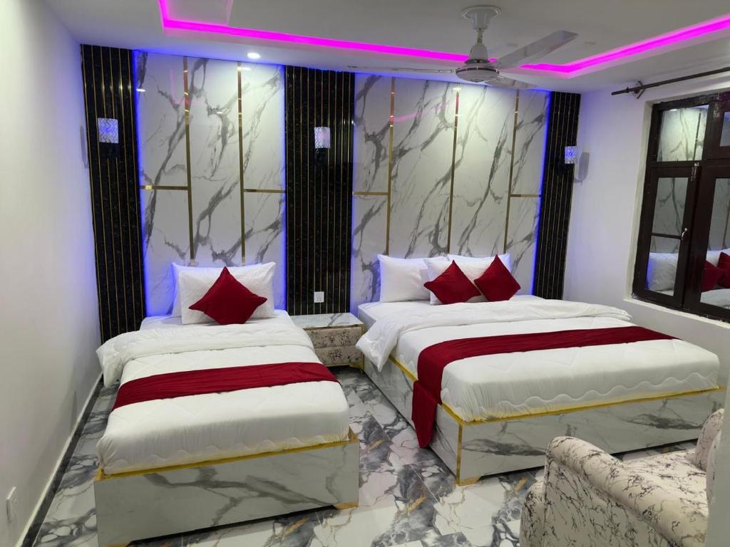 two beds in a room with pink lighting at Decent Luxury Continental in Islamabad