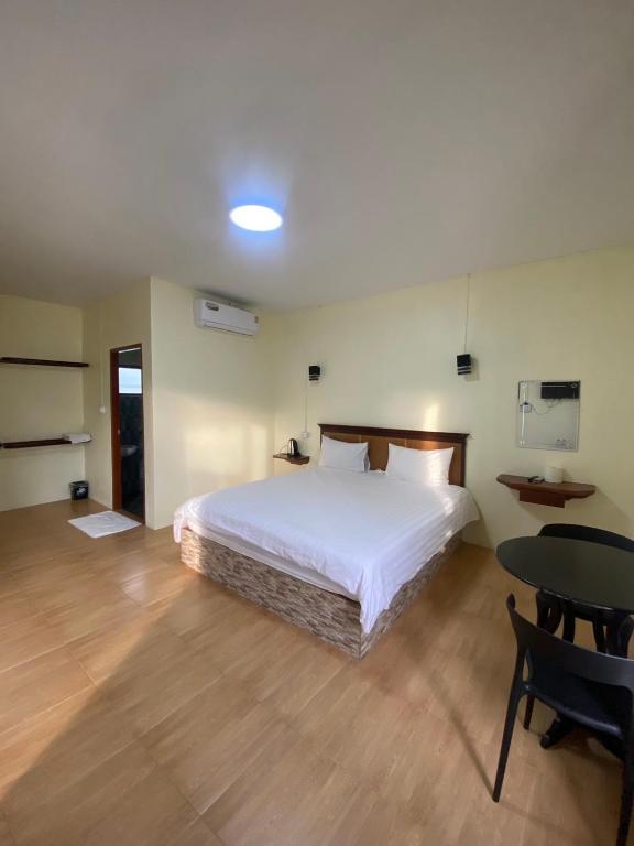 a bedroom with a large white bed and a table at จันผารีสอร์ท By NLG in Ban Khok Khian