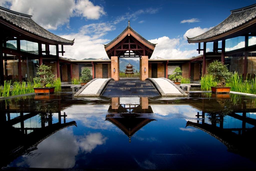 - un bâtiment avec une piscine d'eau en face dans l'établissement Banyan Tree Lijiang, à Lijiang