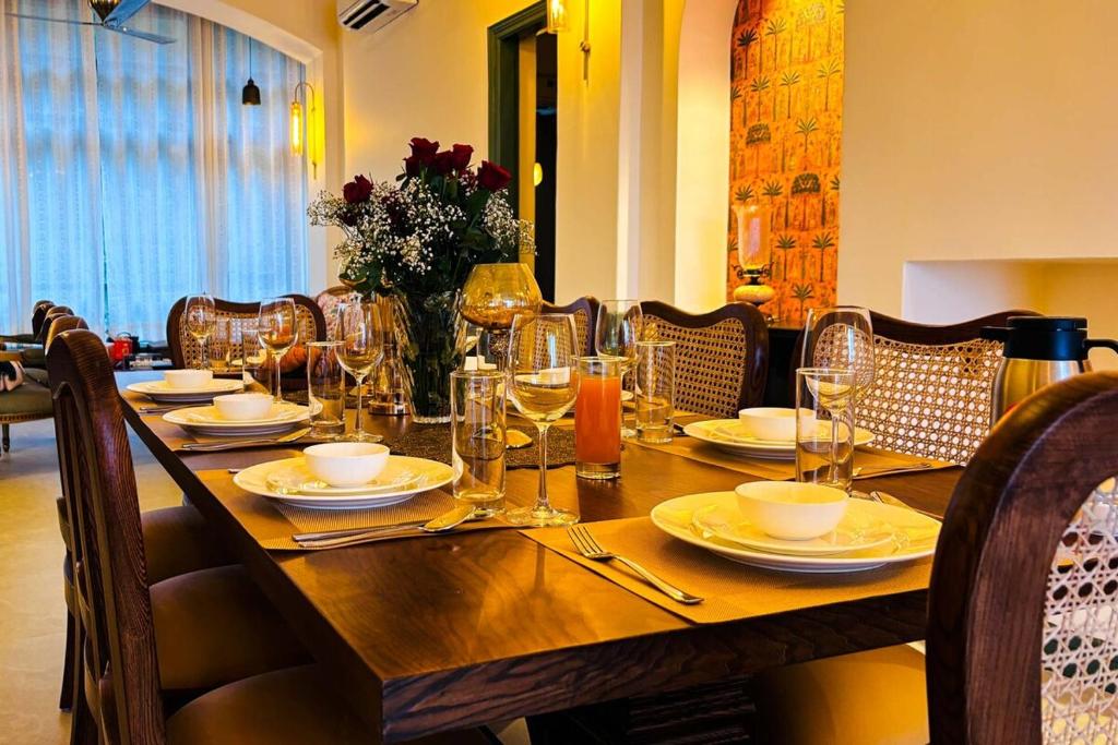a long wooden table with plates and glasses on it at StayVista at Raga Living - Mountain Views, Bonfire in Parwanoo