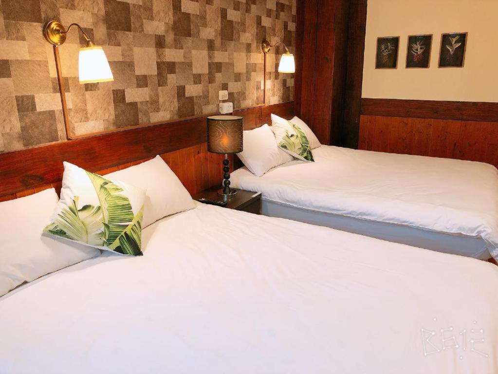 two beds in a hotel room with white sheets at Sun Moon Heart Hostel in Puli
