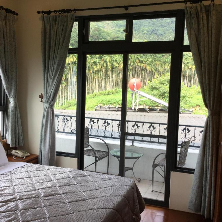 a bedroom with a bed and a view of a balcony at 闕麒景觀民宿Chill Villa B&amp;B in Puli