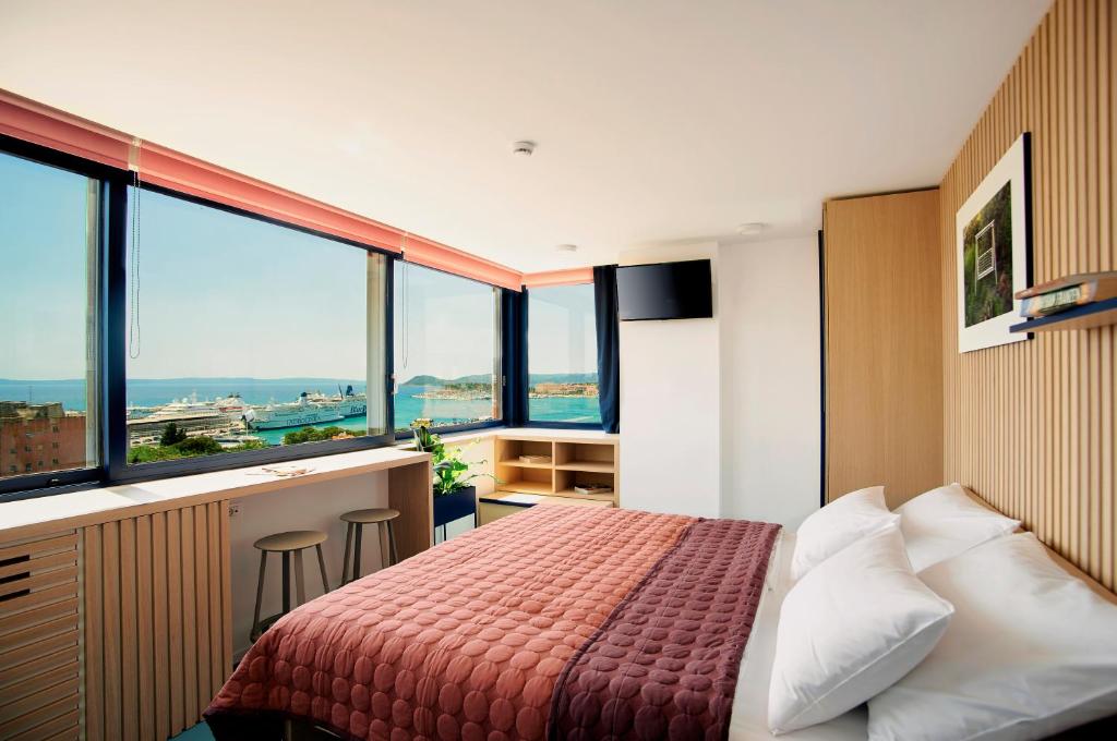 1 dormitorio con 1 cama y barra con ventanas en UP THERE design rooms, en Split