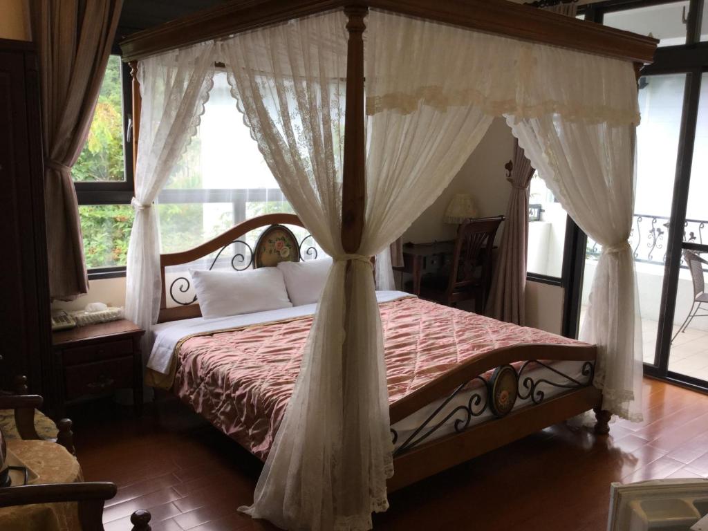 a bedroom with a canopy bed with white curtains at 闕麒景觀民宿Chill Villa B&amp;B in Puli