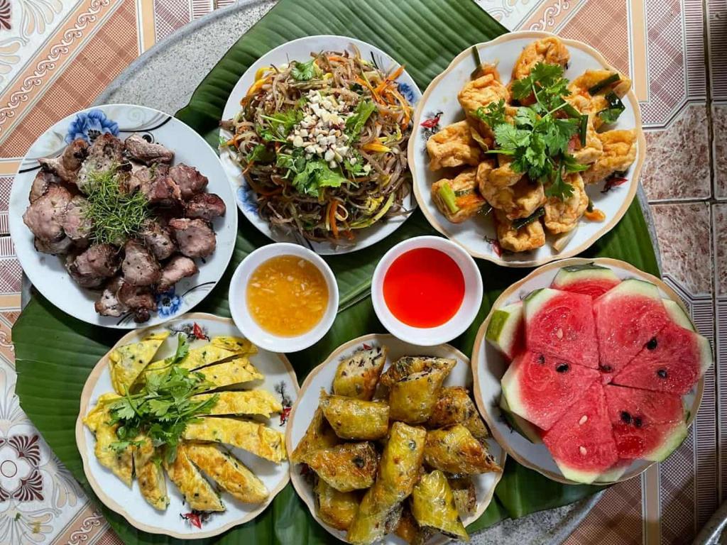 Lũng TiềmにあるHomestay Khánh Pù luôngのテーブルの上にたくさんの食べ物の皿が置かれている
