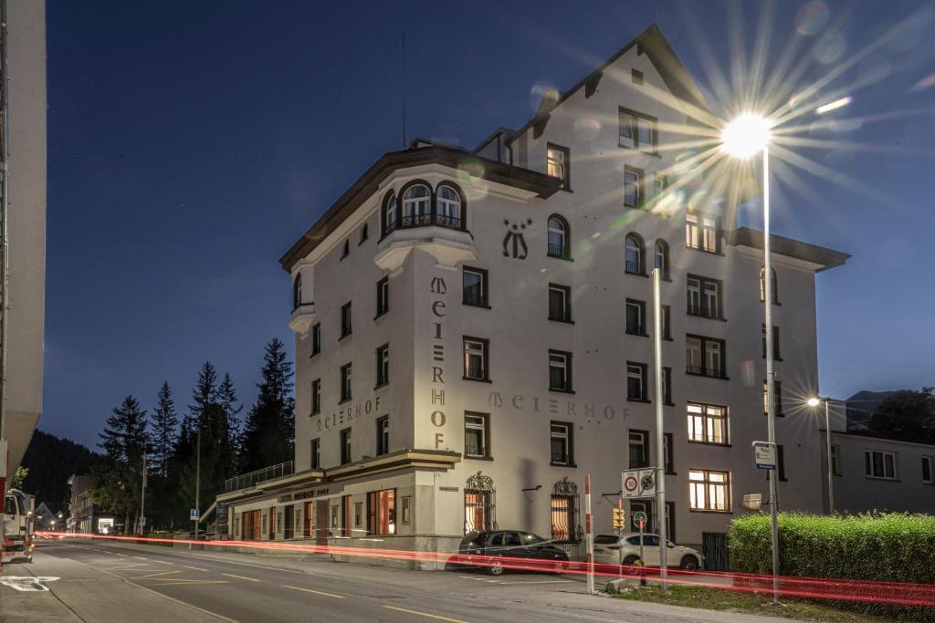 a large white building on a city street at night at Hotel Meierhof in Davos