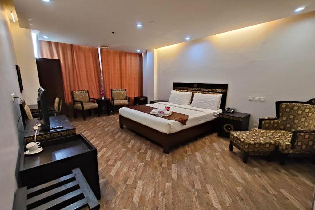 a bedroom with a bed and a desk and chairs at Manila Crown Palace Hotel in Manila