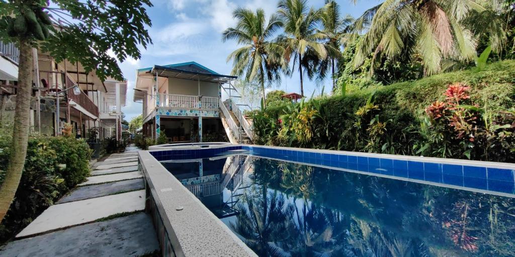 a swimming pool in front of a house with palm trees at Chibel Summer Riverside Resort in El Nido