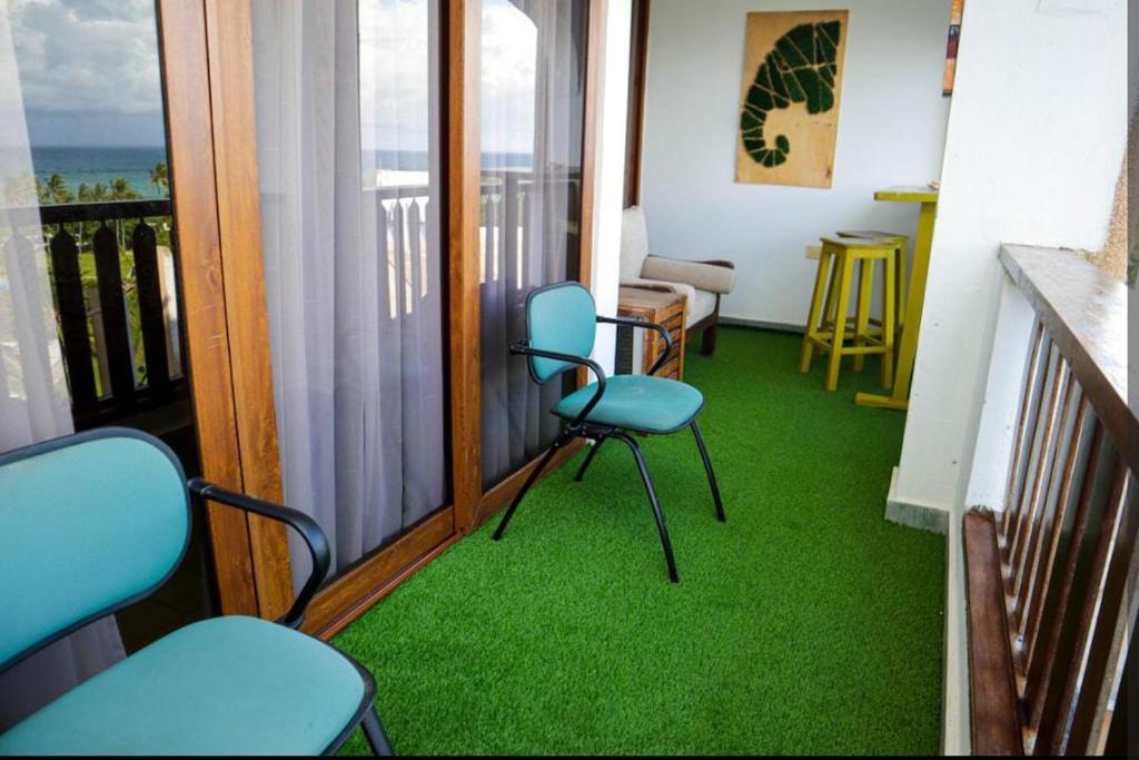 a room with two chairs and a balcony with green carpet at Aruba Home in Kwale