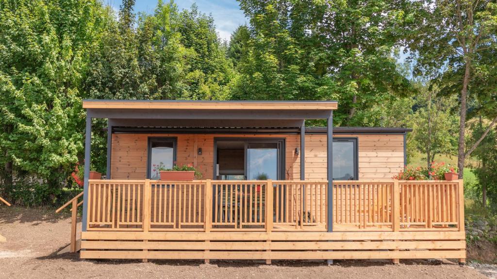 a small cabin with a wooden fence in front of trees at Camping Village Ekar Asiago in Asiago