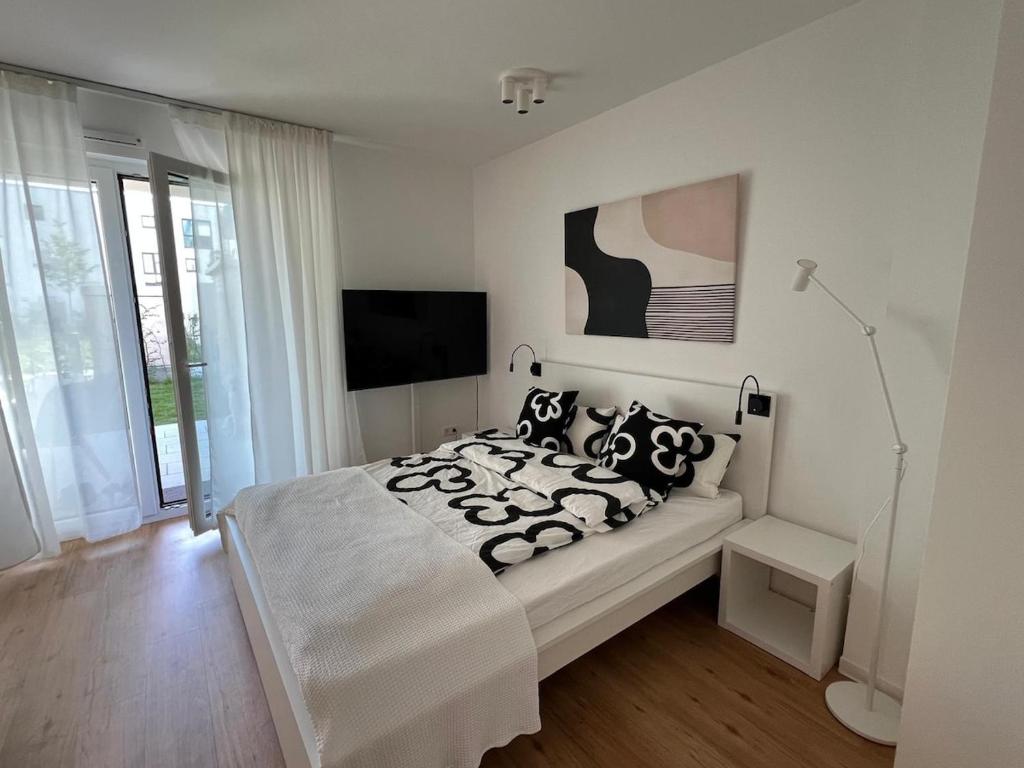 a white bedroom with a bed with black and white pillows at Ferienwohnung mit Garten, Terrasse, Tiefgarage in Zirndorf