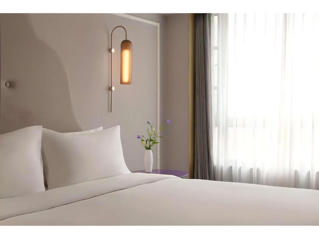 una camera da letto con un letto bianco e una finestra di Mercure Chengdu Jinniu Wanda Plaza a Chengdu