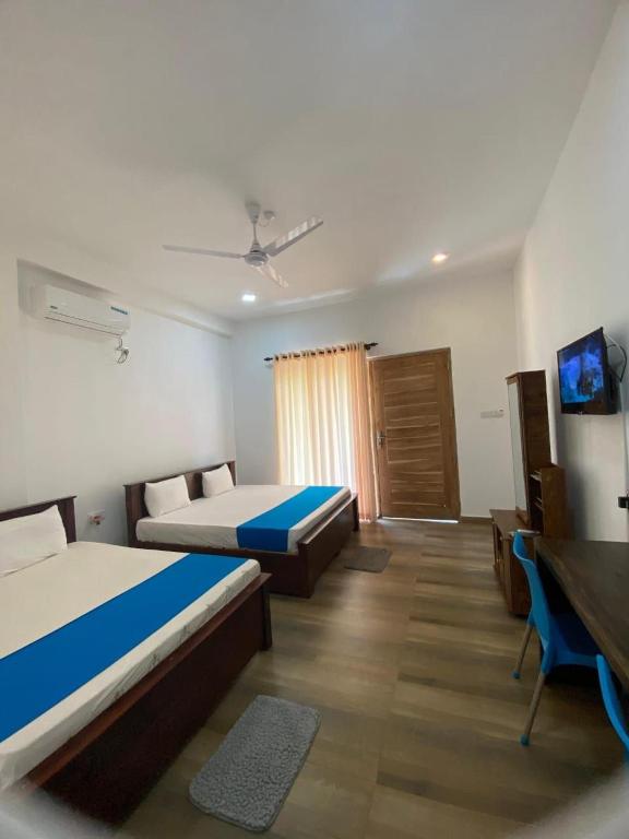 a hotel room with two beds and a desk at Grandmila Resort in Anuradhapura
