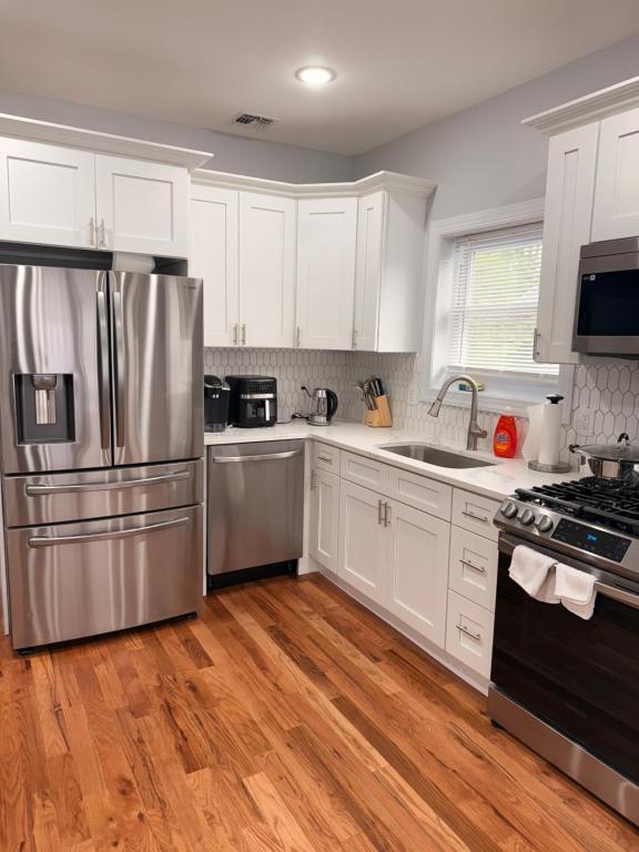 een keuken met witte kasten en een roestvrijstalen koelkast bij The great homes in East Orange