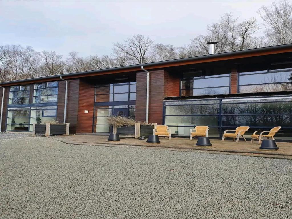 Chalet in Odeigne with Private Pool & Sauna في Manhay: مبنى امامه مجموعه من الكراسي