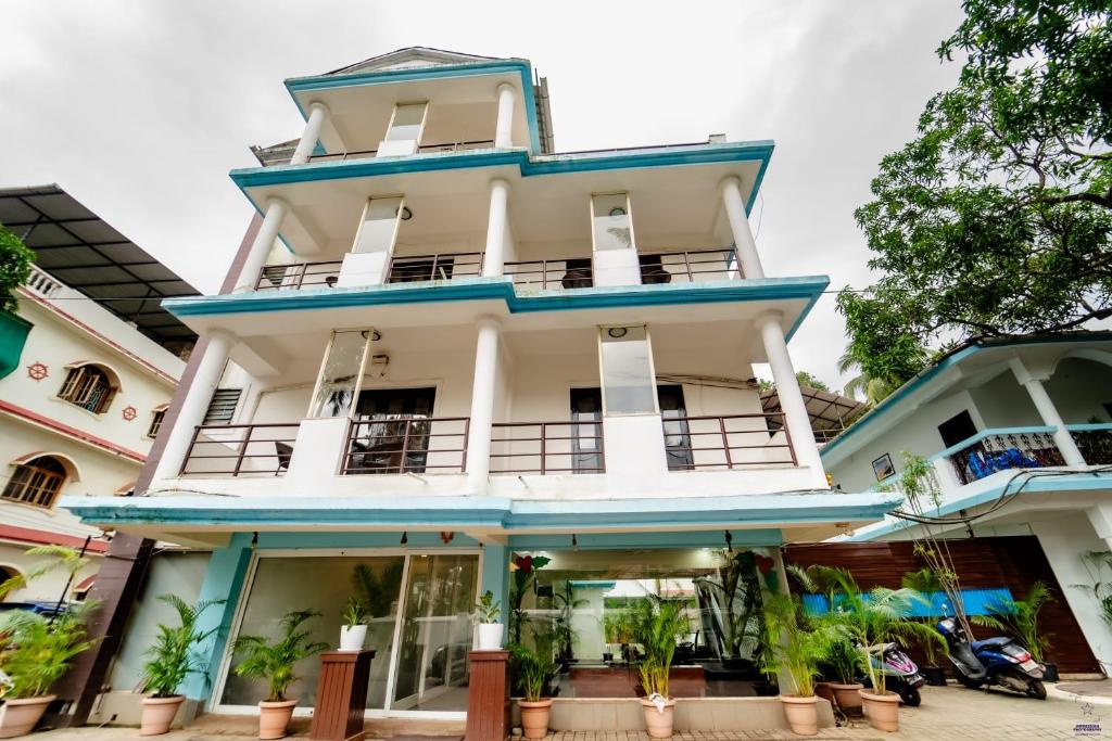 un grand bâtiment blanc avec des finitions bleues dans l'établissement Mint By SR, à Calangute