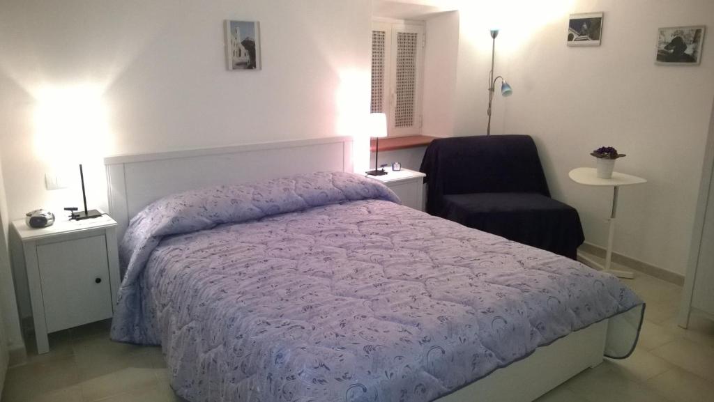 ein Schlafzimmer mit einem Bett mit einer lila Bettdecke und einem Stuhl in der Unterkunft B&B I Tre Bassotti in Loreto