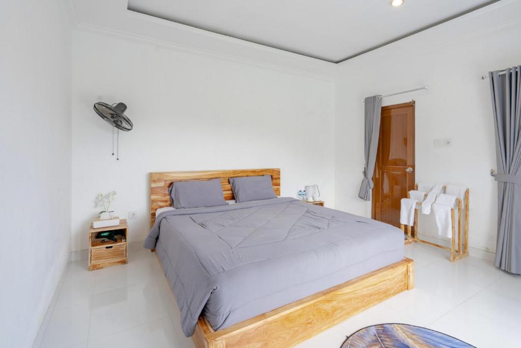 a bedroom with a large bed in a white room at Batur Kencana Villa Mitra RedDoorz in Baturaja