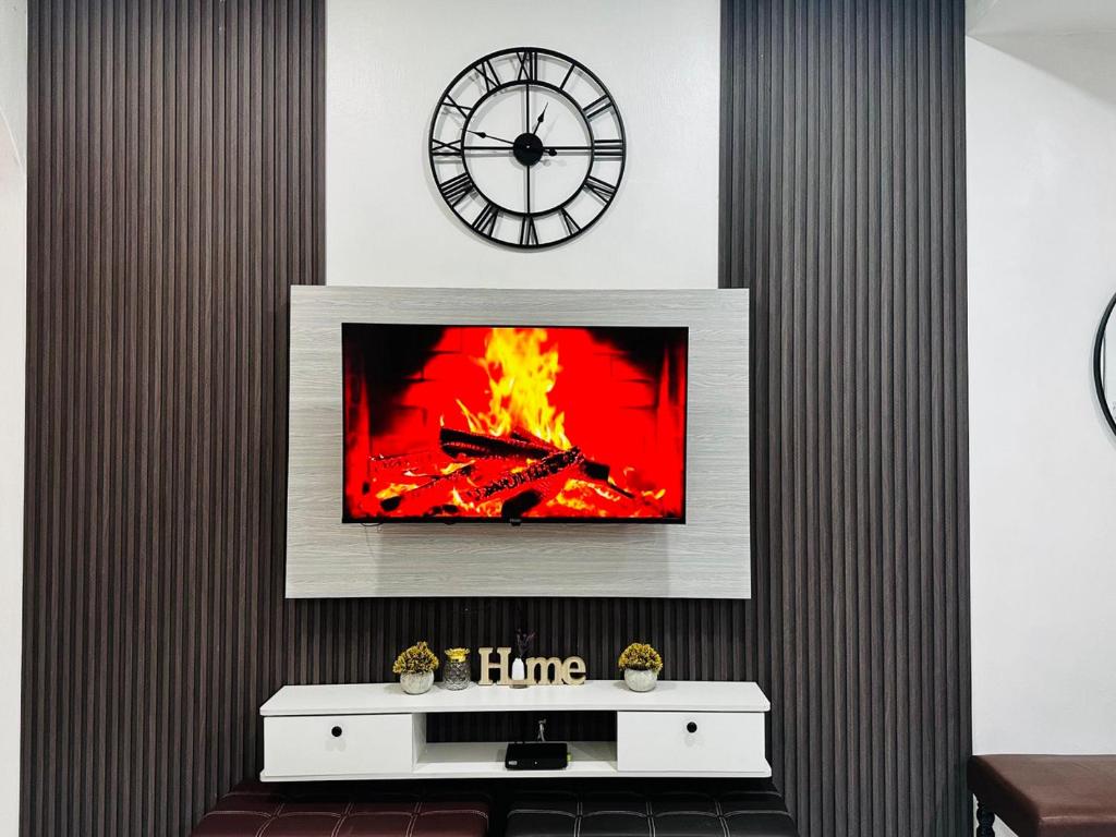 a living room with a fireplace with a tv and a clock at Effa Homestay in Sungai Petani
