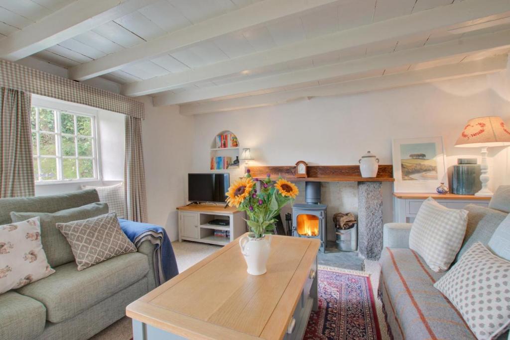 Una sala de estar con un sofá y una chimenea. en Mimosa, en Helford