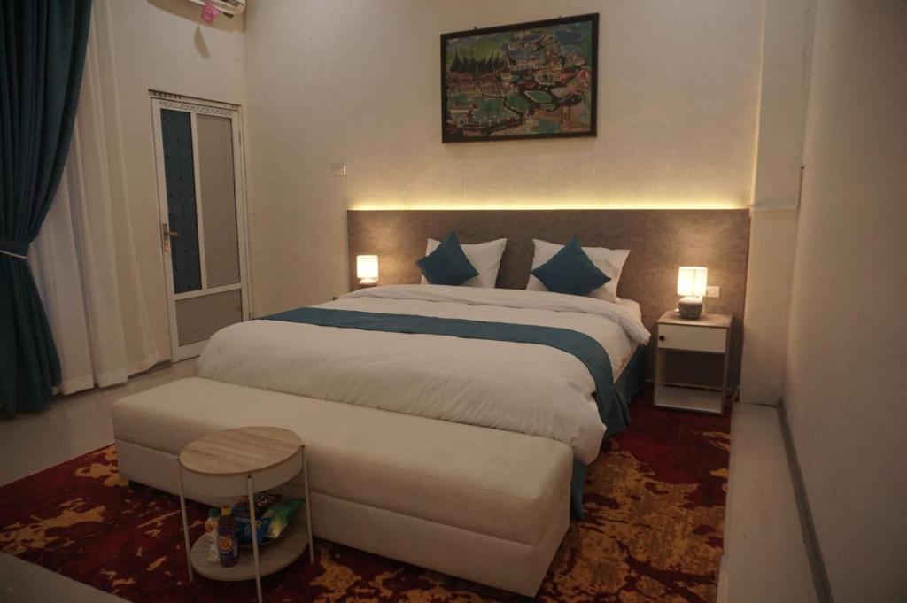 a hotel room with two beds and two tables sidx sidx sidx at Grand Aulia Hotel Padang Panjang in Padangpanjang