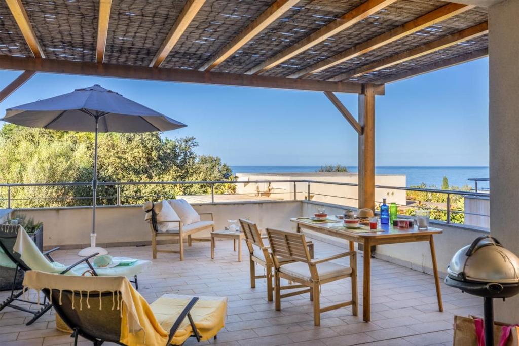 een terras met een tafel, stoelen en een parasol bij Casa Mediterranio in Lumio