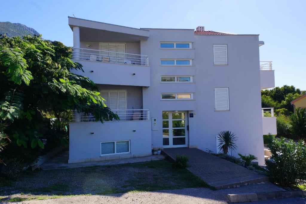 un edificio de apartamentos blanco con balcón en Apartments Sunny, en Karlobag