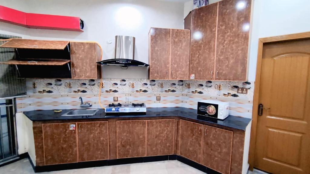 a kitchen with wooden cabinets and a sink at Star Guest House in Jhelum