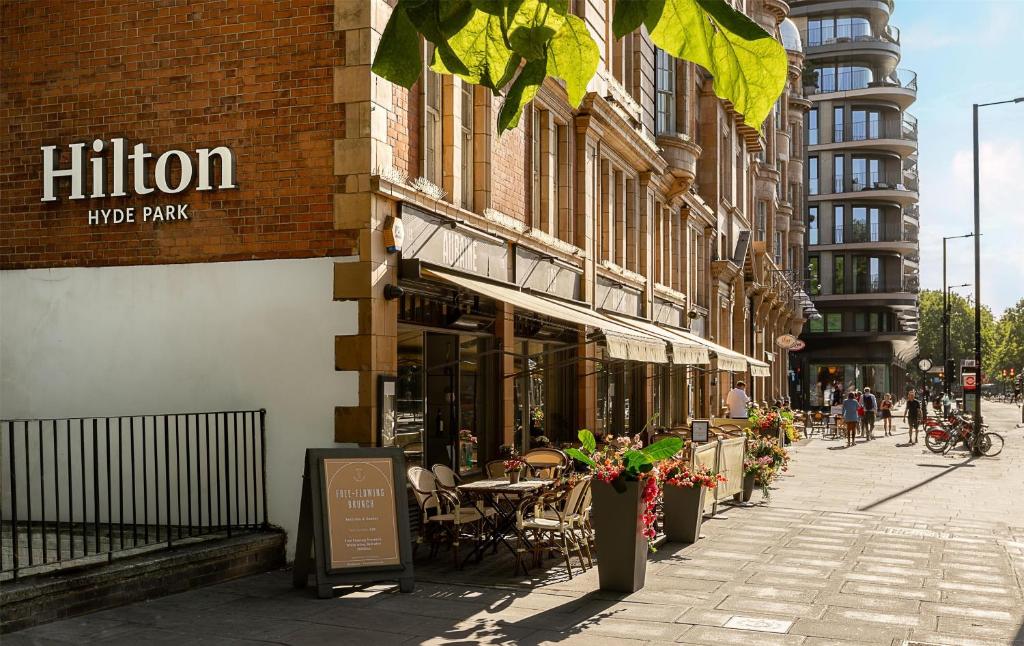 a street with tables and chairs outside of a building at Hilton London Hyde Park in London