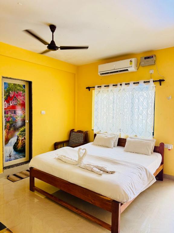 a bedroom with a large bed with yellow walls at Chelsea inn in Calangute