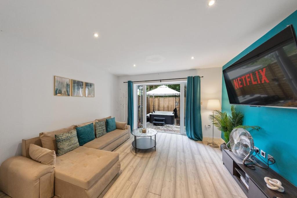 Luxury 4BR Home with Hot Tub, Sleep 8, Free Parking, Garden في Kenley: غرفة معيشة مع أريكة وتلفزيون بشاشة مسطحة