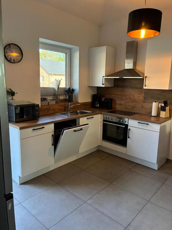 a kitchen with white cabinets and a sink at Gemütliches Ferienhaus mit Sauna an der Nordsee in Sehestedt