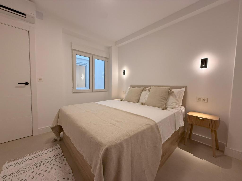 a white bedroom with a large bed and a window at NEW - Old Town Modern Apartment Close to Beach in Estepona