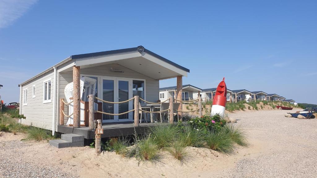 una casa pequeña en la playa con un faro rojo en Ostseeferienpark Walkyrien - Kapitän 20, en Kagelbusch