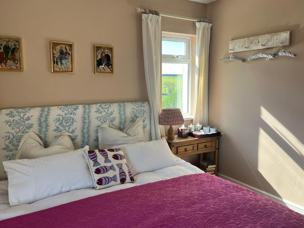 a bedroom with a bed with a purple blanket and a window at Hope Valley House BnB in Kingsbridge