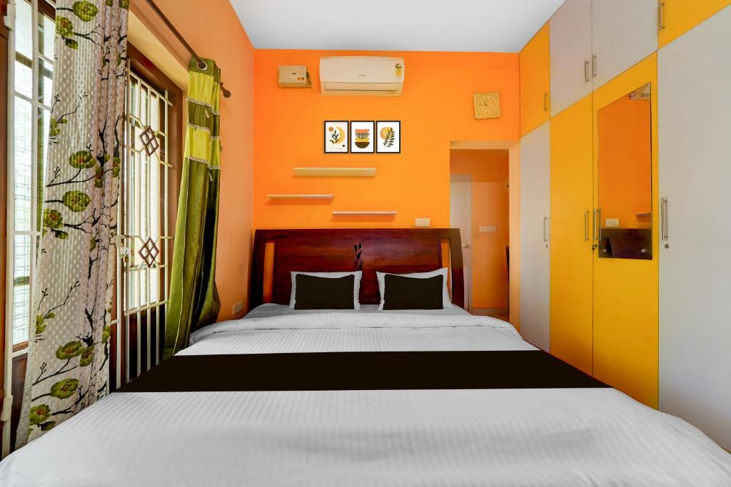 a bedroom with a bed with an orange wall at Collection O Balaramapuram White Castle in Kovalam