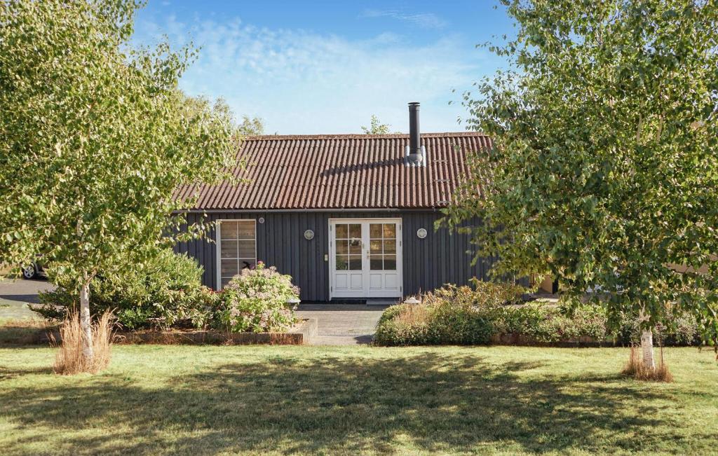 a black house with a white door and trees at 2 Bedroom Cozy Home In Hasle in Vysteby