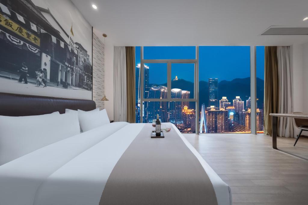 a bedroom with a large white bed with a city view at YANG TRAVEL Hotel 重庆解放碑洪崖洞店 in Chongqing