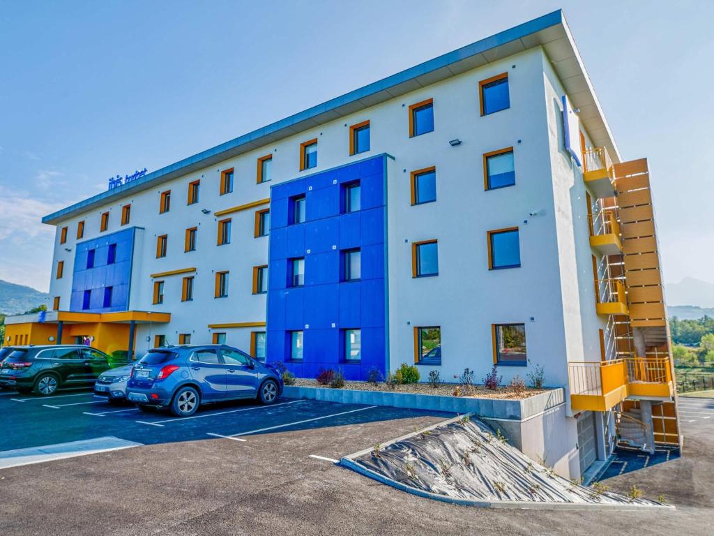 a building with cars parked in a parking lot at Ibis Budget Nangy Annemasse in Nangy