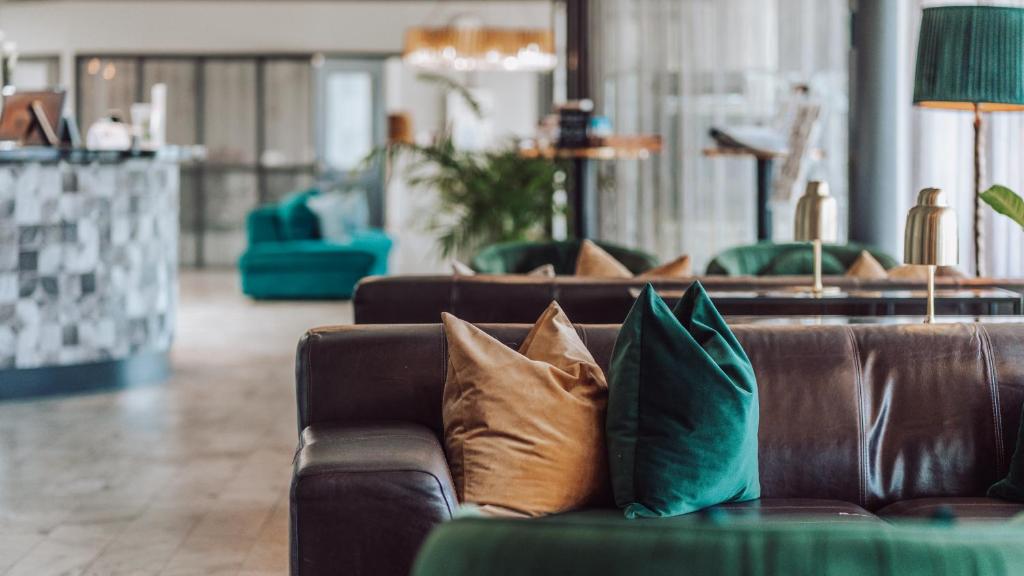 a brown leather couch with pillows in a living room at Apple Hotel &amp; Konferens Göteborg in Gothenburg