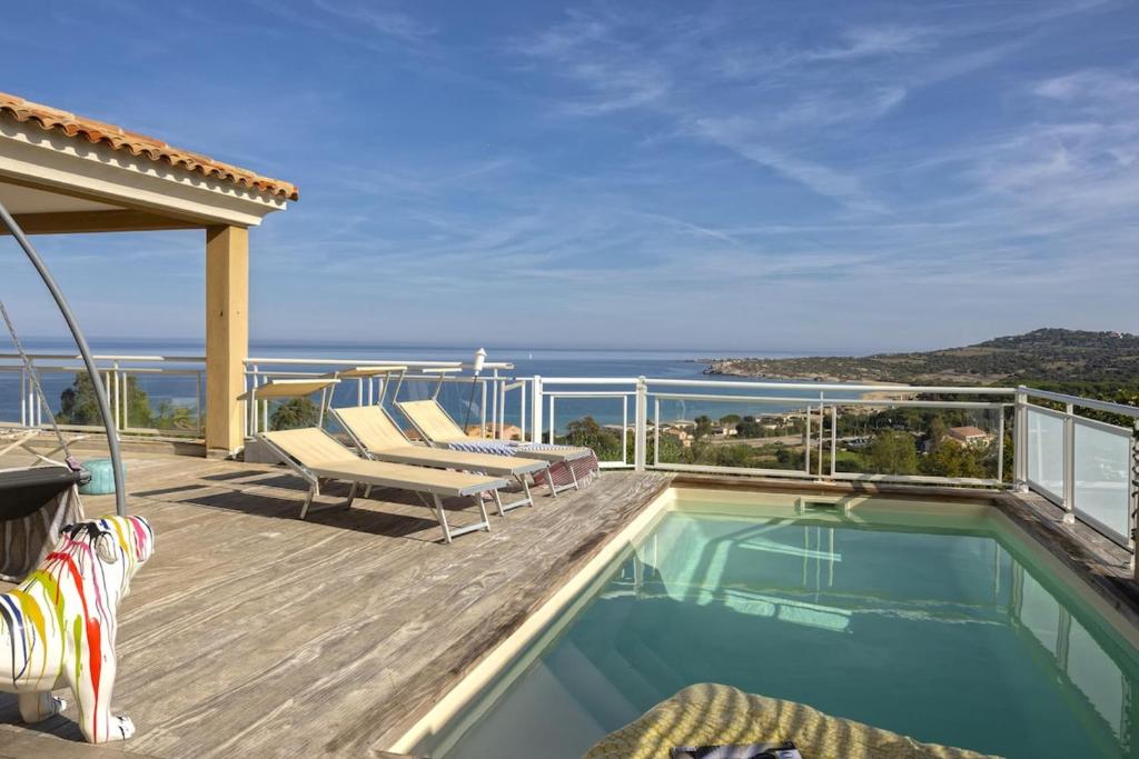 a swimming pool on a deck with a view of the ocean at Villa Carlisa in Algajola